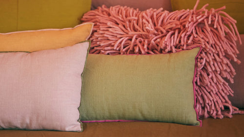green pink and yellow pillows in a reading nook in front of a window in a patio