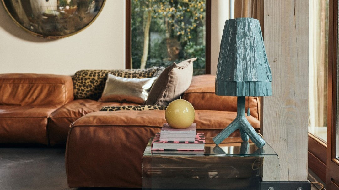 brown leather sectional with pillows and blue wooden table lamp