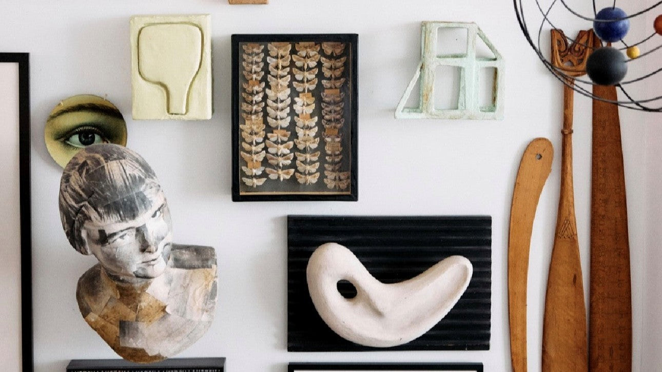 large photo art work in white wooden frame behind a velvet brown club sofa with a large wooden sculpture next to it