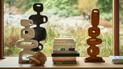 large photo art work in white wooden frame behind a velvet brown club sofa with a large wooden sculpture next to it