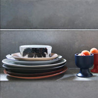 Stack of ceramic plates and bowls on a gray surface with a gray wall background