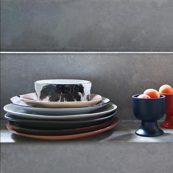 Stack of ceramic plates and bowls on a gray surface with a gray wall background