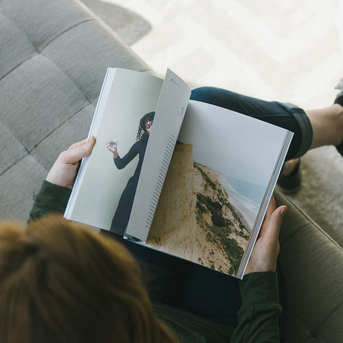 Person holding a book with scenic images of a woman and a coastal landscape.