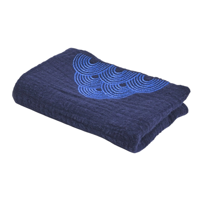Folded navy blue blanket with a blue embroidered design on a white background