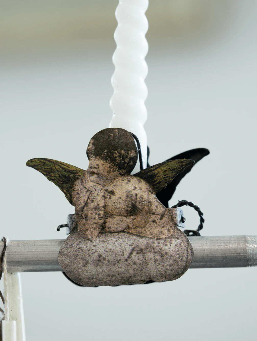 Antique candle holder clip shaped of angel on cloud on a branch with a blurred background