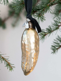 Decorative glass pickle Christmas ornament hanging on a Christmas tree branch.