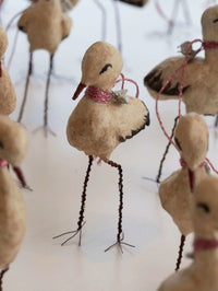 Textured stork figurines with wire legs on a white background