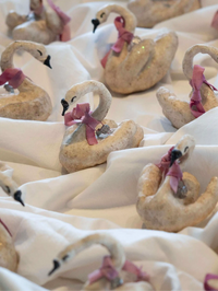 Decorative swan figurines with pink bows on a white surface