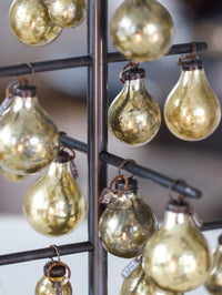 Decorative gold glass bulbs hanging from a metal stand.