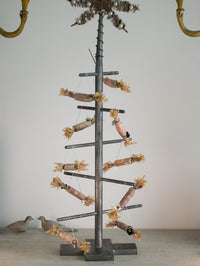 Decorative metal tree with branches and small paper crackers on a plain background