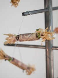 paper Christmas cracker with flower hanging on a rack against a white wall