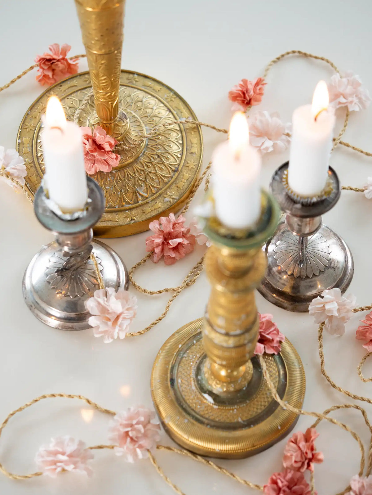 Decorative candle holders with candles and flowers on a light background