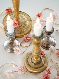 Decorative candle holders with candles and flowers on a light background