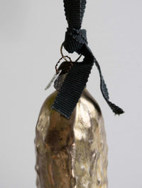 Gold pickle ornament with a black cord on a light gray background