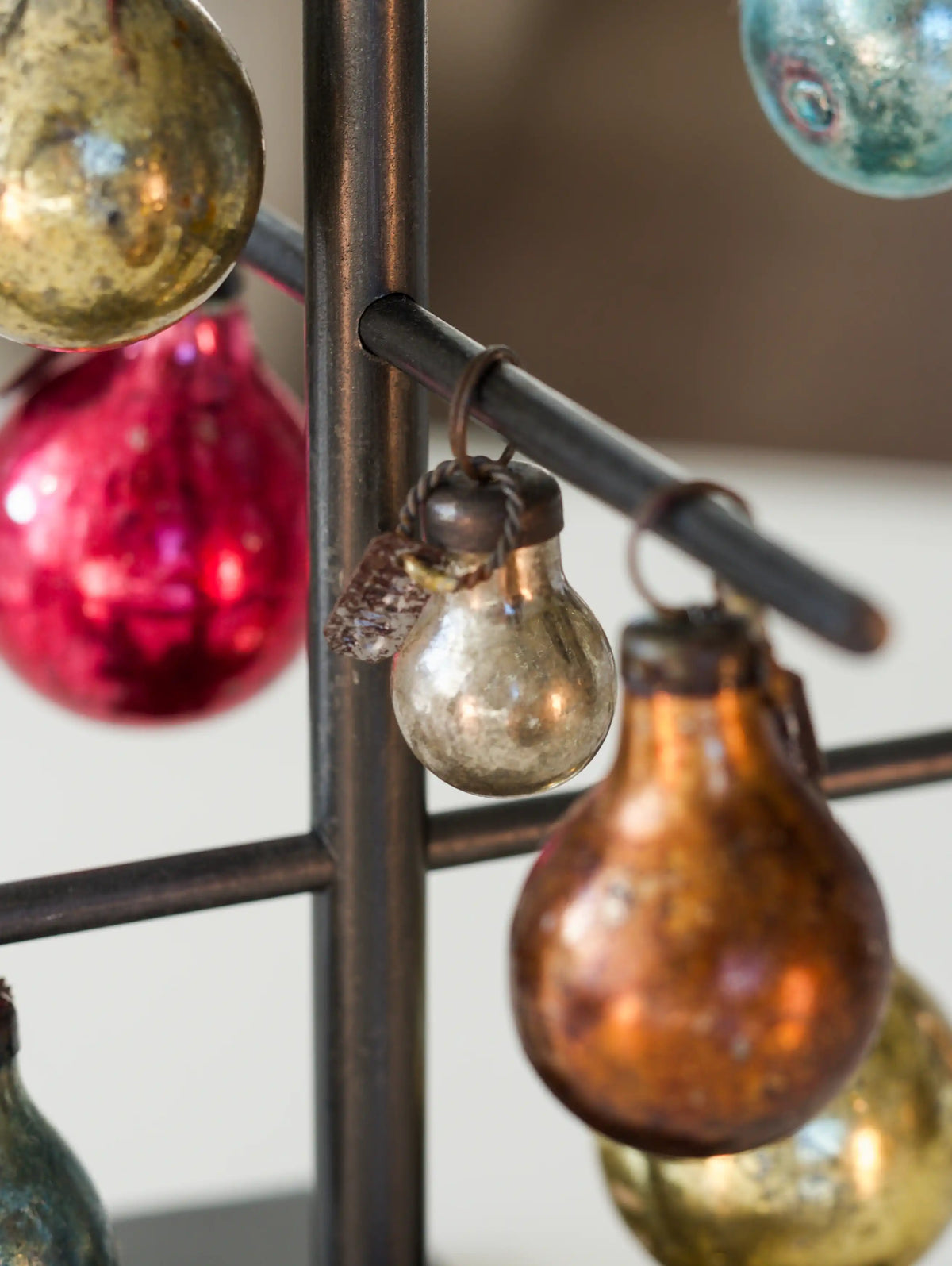 Decorative glass bulbs hanging from a metal rod with a blurred background