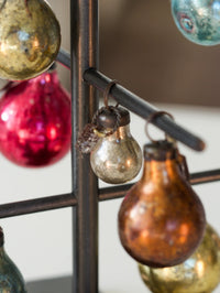 Decorative glass bulbs hanging from a metal rod with a blurred background