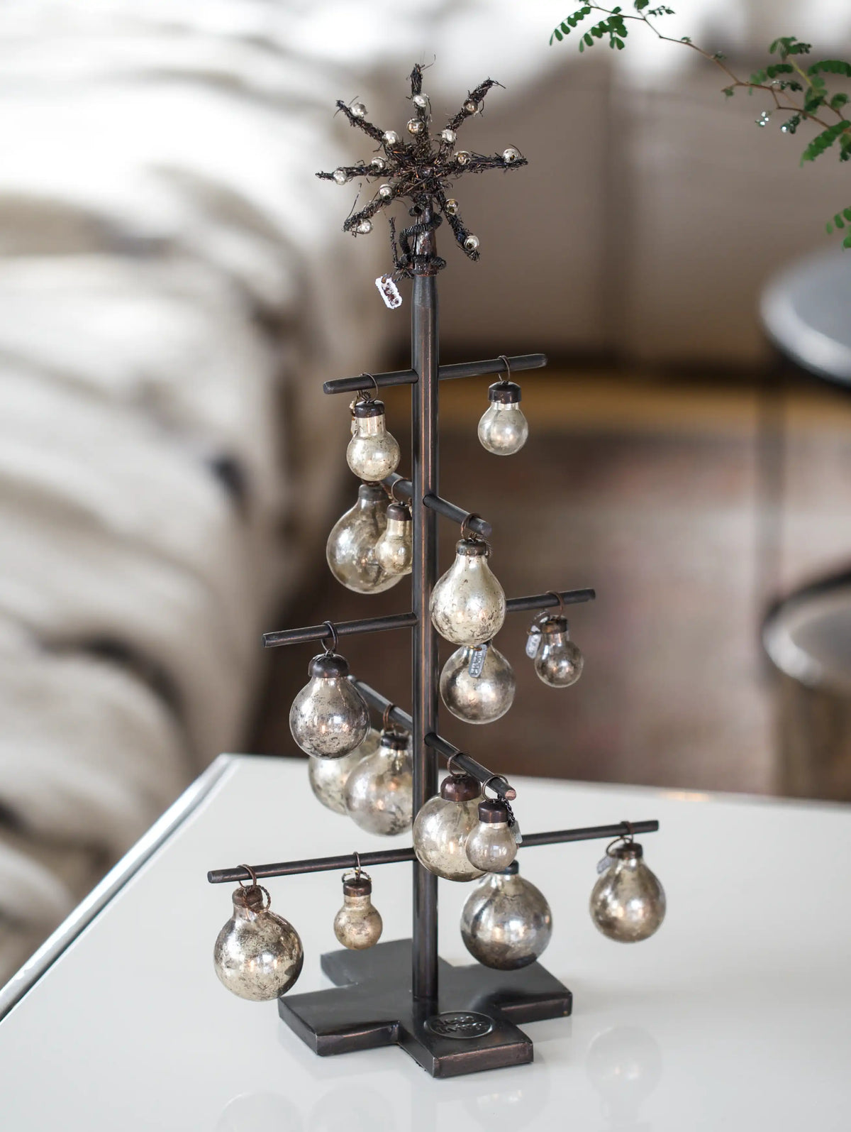 Decorative metal tree with hanging bulbs on a white surface