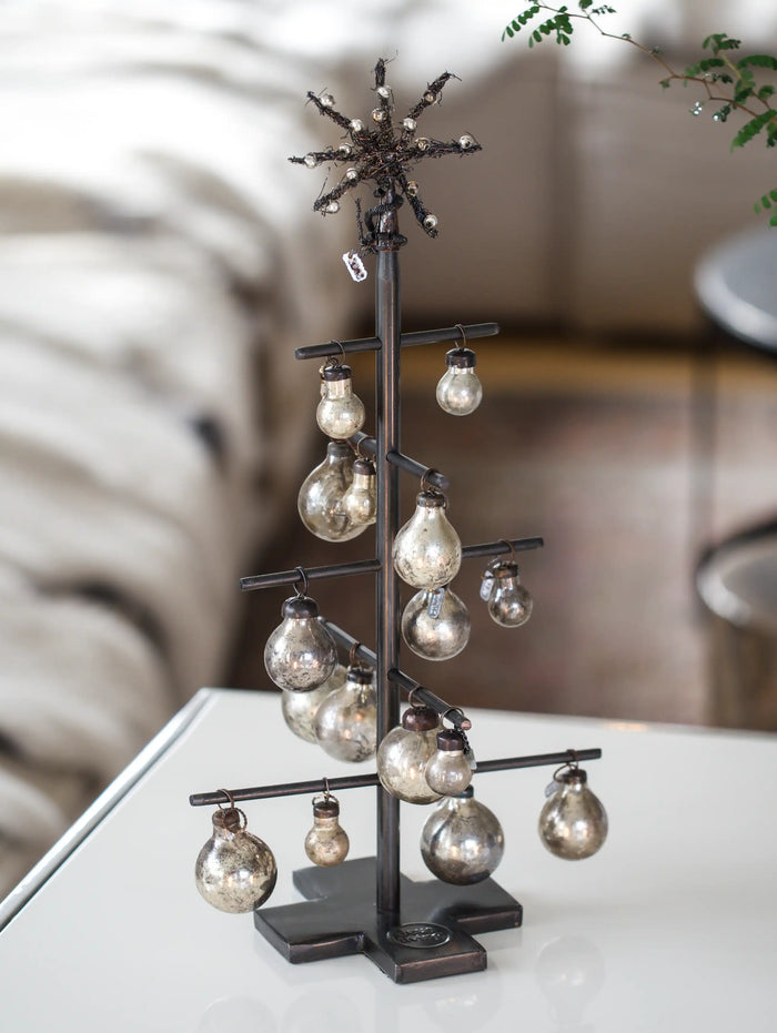 Decorative metal tree with hanging bulbs on a white surface