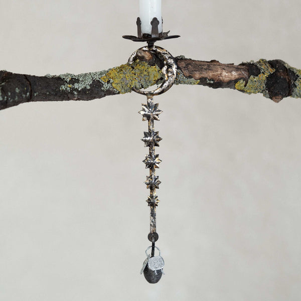 Decorative hanging candle holder with star-shaped design on a branch against a neutral background