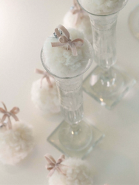 Clear glass candle holders with white wool snowball and pink ribbons on a white background