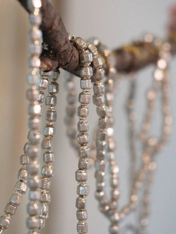 Close-up of a decorative garland with hexagonal beads on a wooden branch.