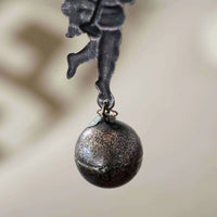Decorative metal figure with a ball on a blurred background