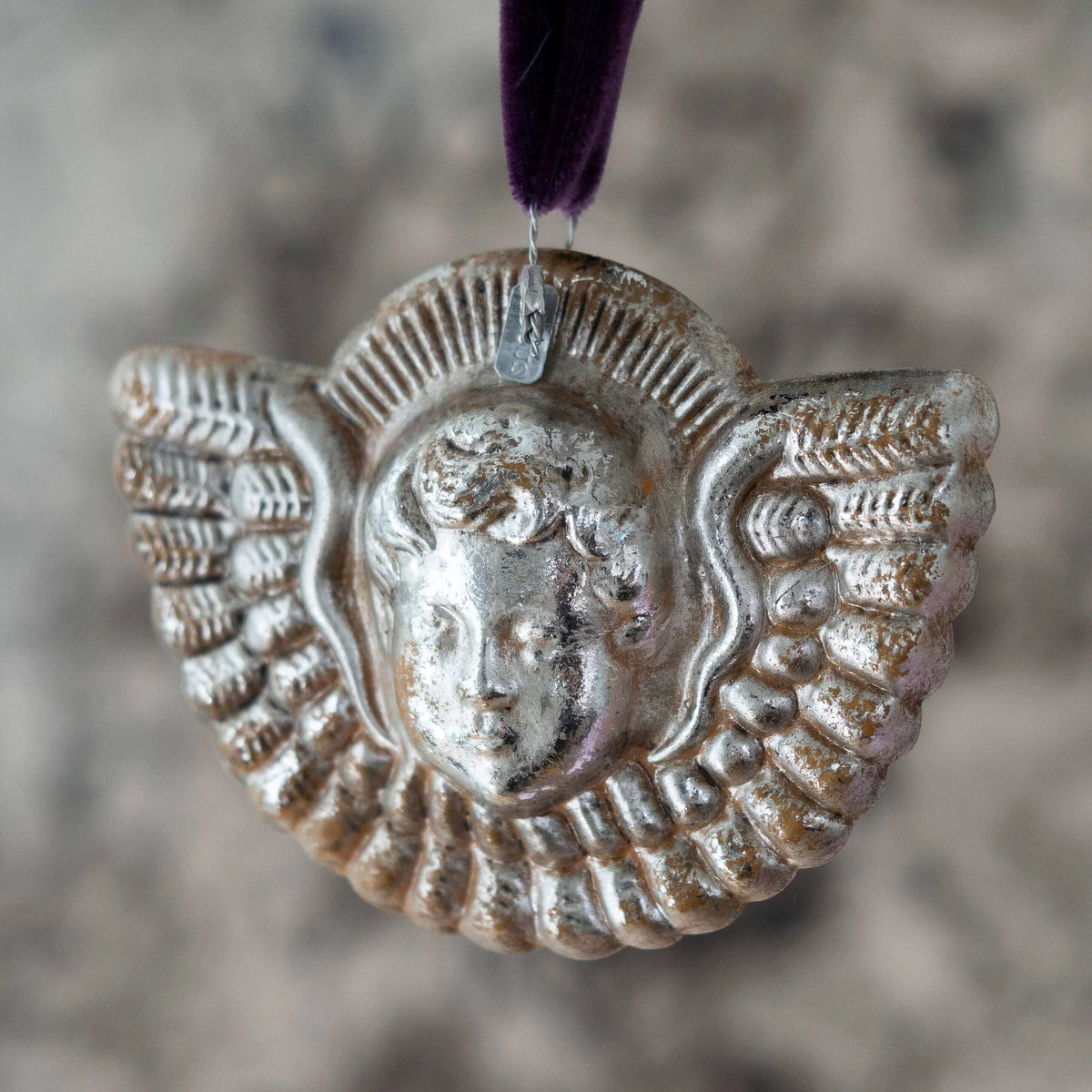 Decorative silver pendant with a face design on a blurred background