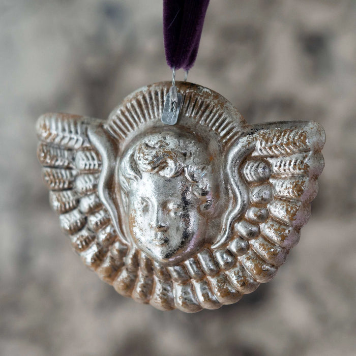 Decorative silver pendant with a face design on a blurred background