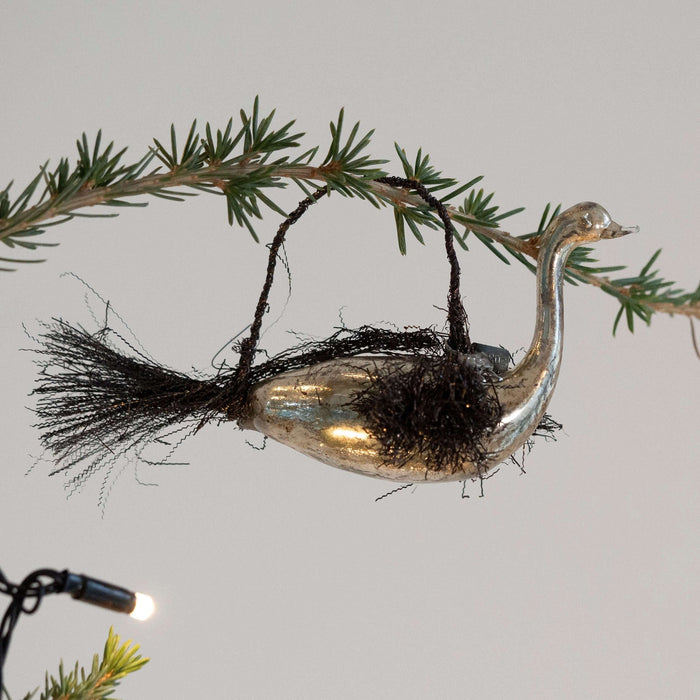 Decorative bird ornament on a branch with a plain background
