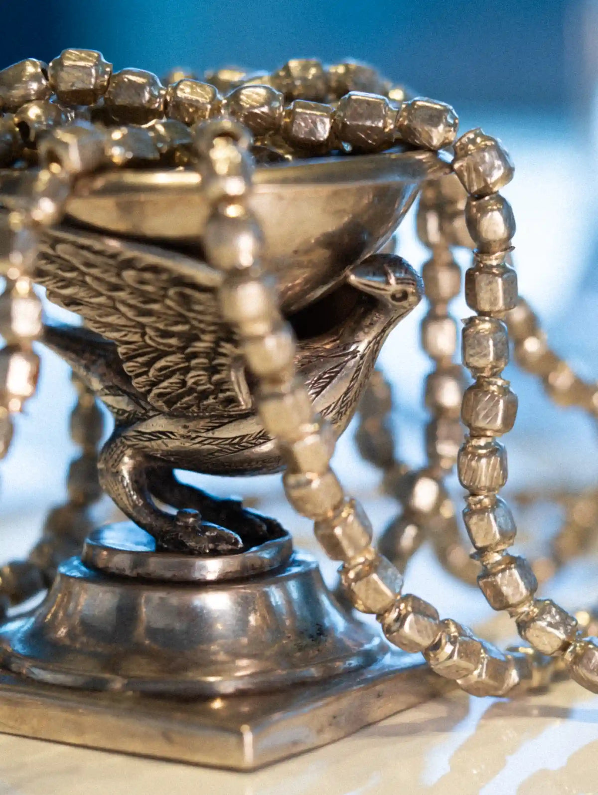 Silver incense bowl with beaded chain on a blurred background
