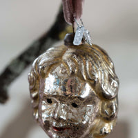 Silver face-shaped ornament on a branch