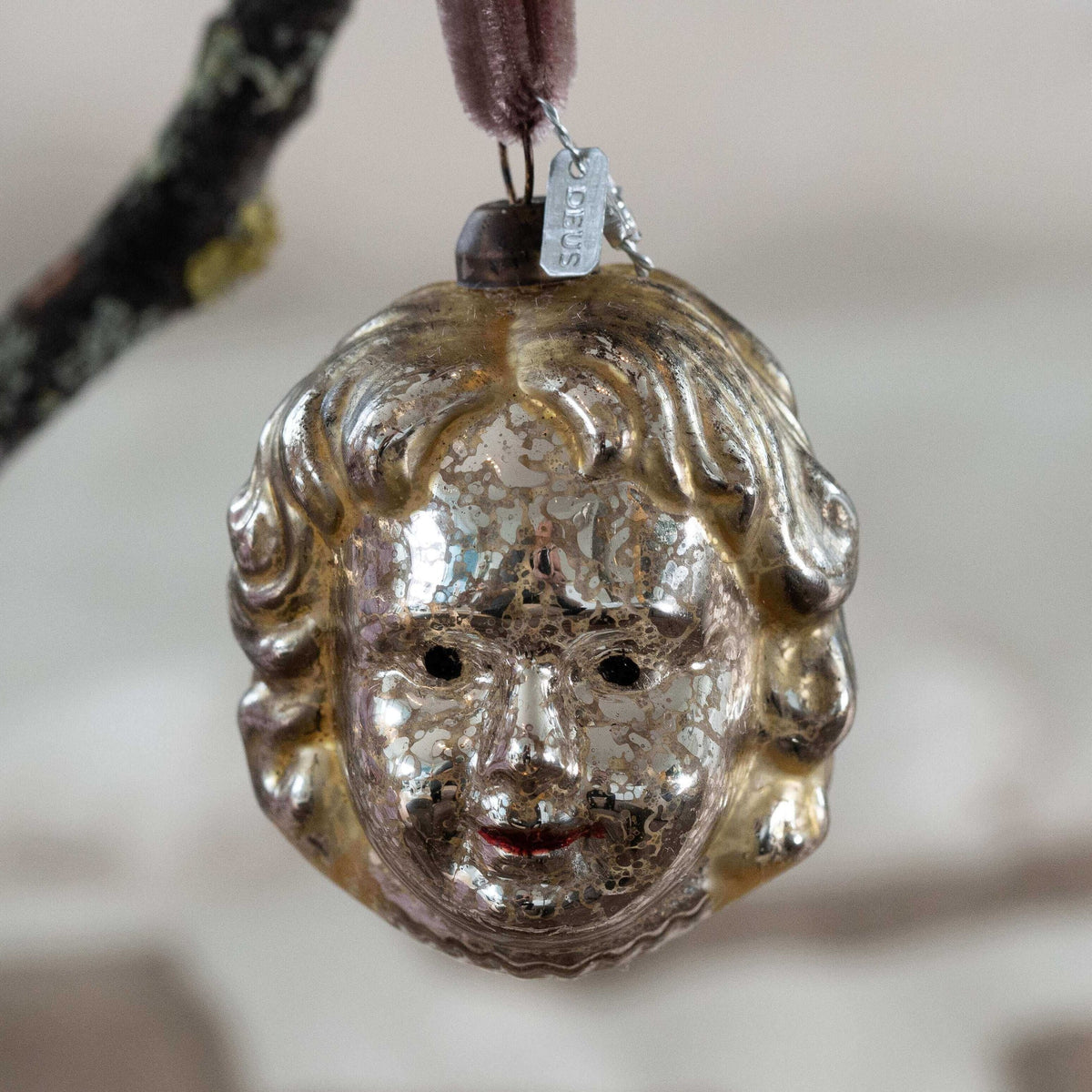 Decorative glass angel face pendant with intricate details on a blurred background