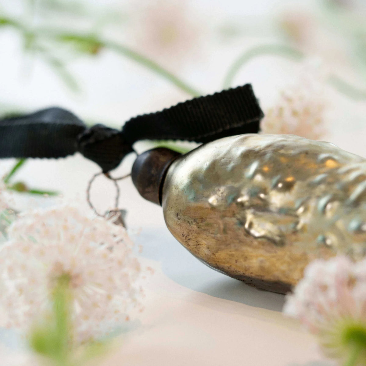 Decorative pickle Christmas ornament with a black ribbon on a blurred natural background