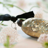 Decorative pickle Christmas ornament with a black ribbon on a blurred natural background