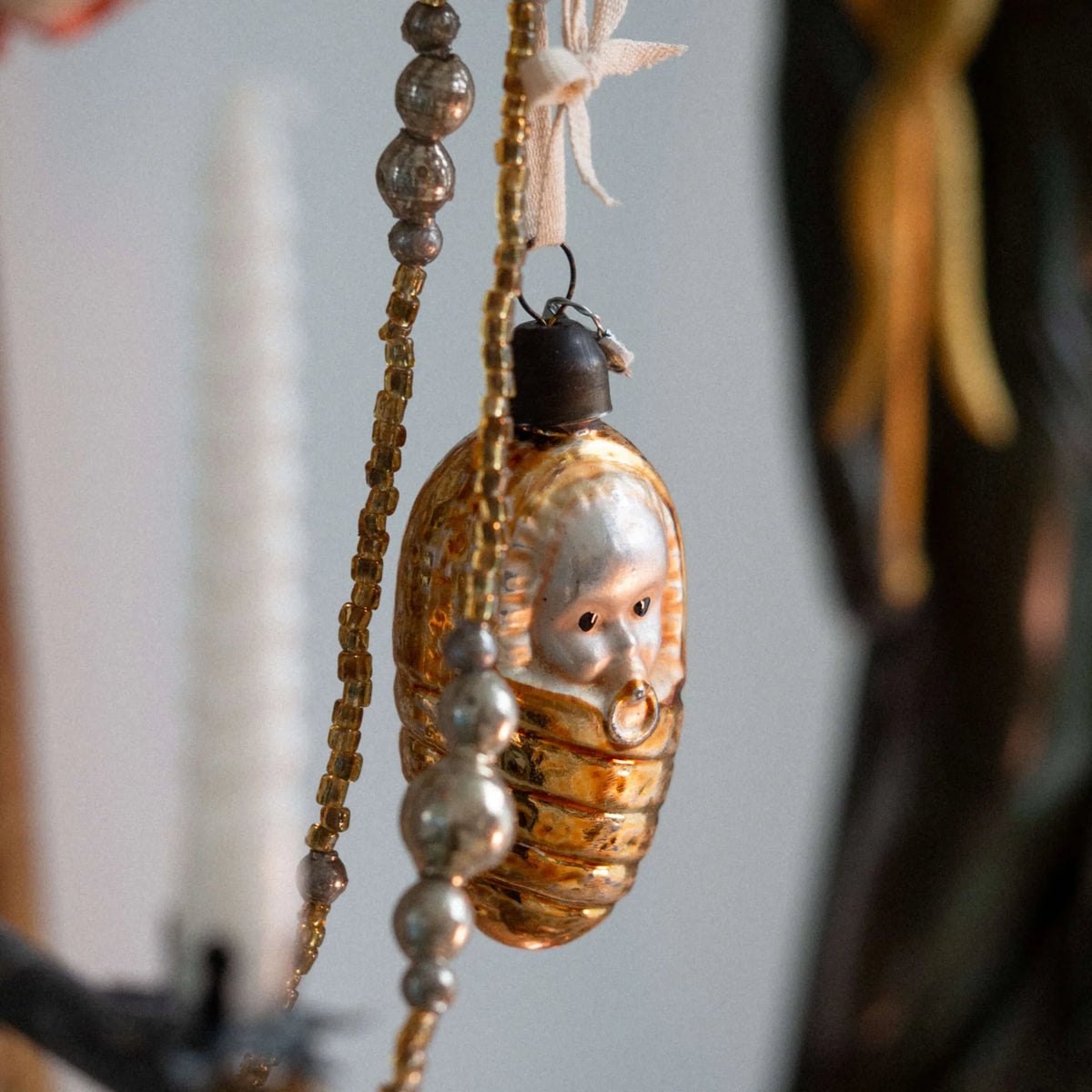 Decorative ornament with face design hanging against a neutral background