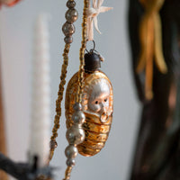 Decorative ornament with face design hanging against a neutral background