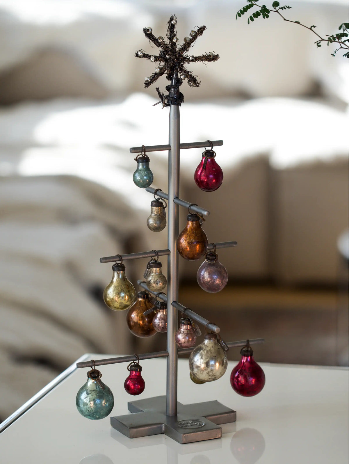 Decorative metal tree with colorful ornaments on a blurred background