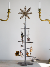 Decorative metal tree with ornaments and candles on a plain background