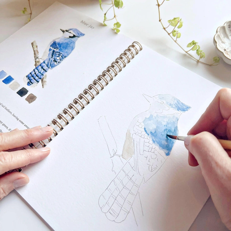 open water coloring book with image of bird and hand holding brush