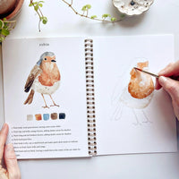 open water coloring book with image of bird and hand holding brush