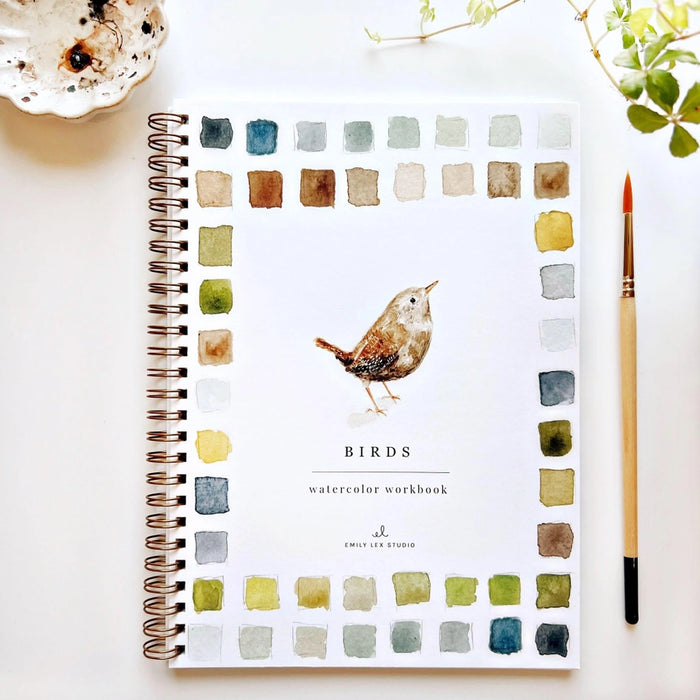 paper water coloring book with bird and brush on white table