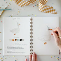 hand holding a brush, coloring a duck with a party hat