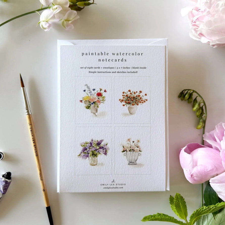 cover of paintable watercolor notecards with illustration of 4 bouquets in different colors on a desk with a brush an flowers