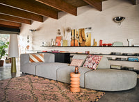 peach and cream colored striped lumbar shape pillow on a gray sofa