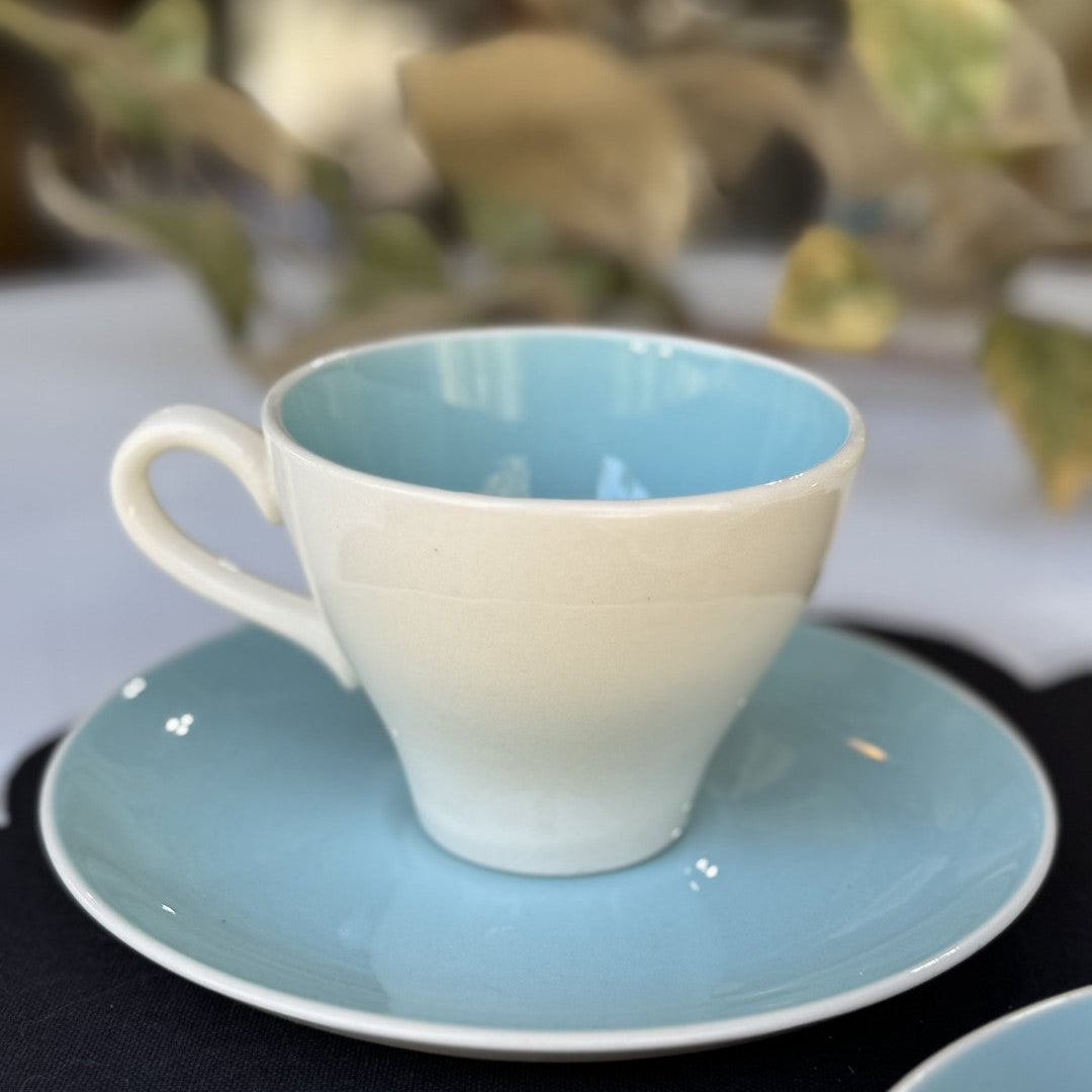 Ceramic cup and saucer with a gradient blue design on a dark surface.