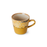 Yellow ceramic mug with speckled pattern on a white background
