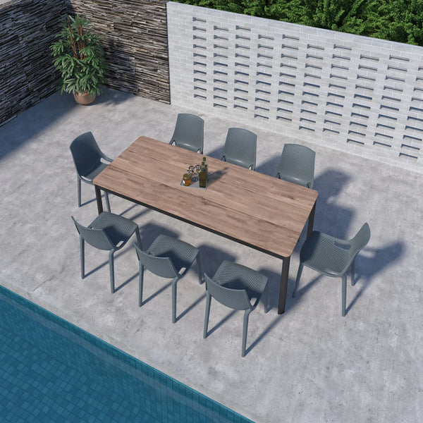 Outdoor dining set with a wooden table and gray chairs by a pool.