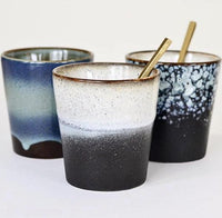 Three ceramic cups with gradient colors and gold straws on a white background