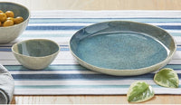 reactive glaze blue, organic shaped salad plate with two bowl on a table with a striped runner