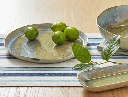 large plate with glossy finish, limes and a lime leave on a table with a striped runner